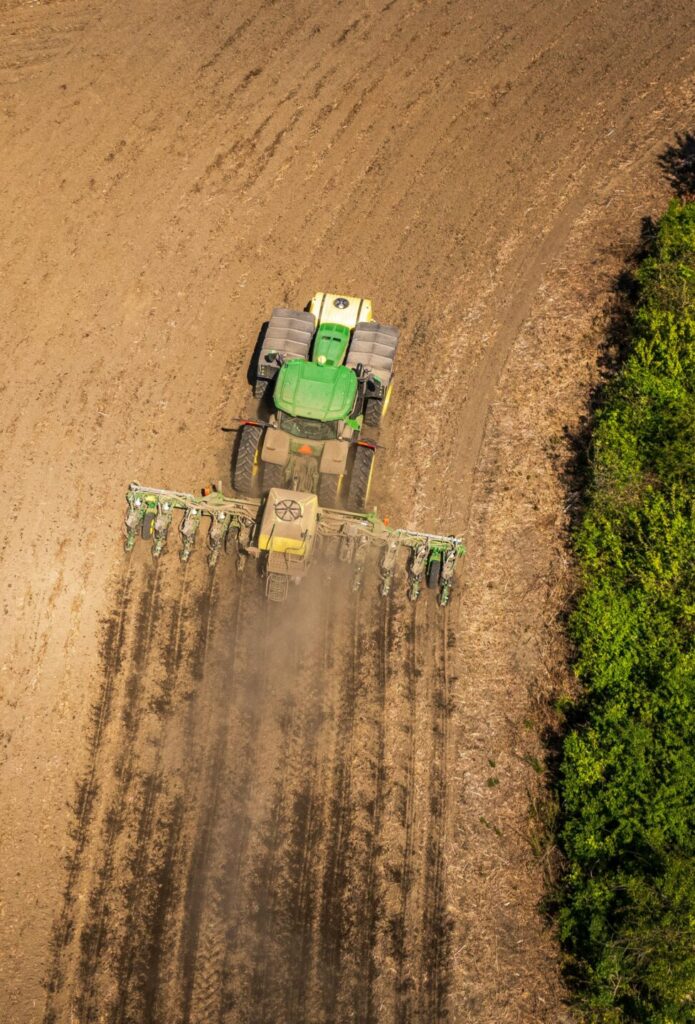 Drone Shot of a Tractor with a Seeder on a Cropland